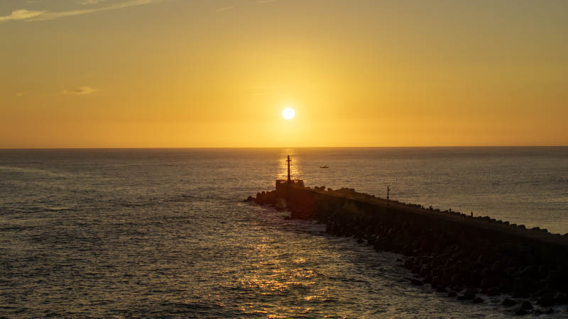 夕阳下的灯塔与海堤图片