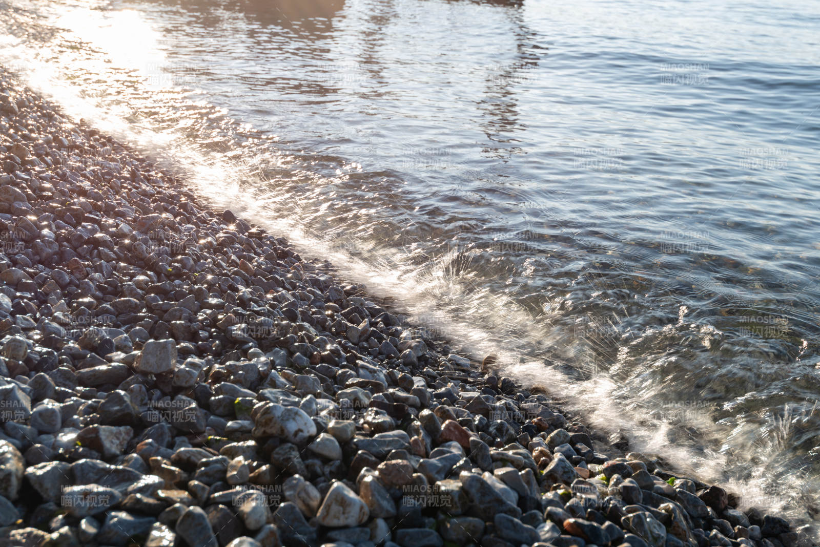 夕阳下的石滩与波浪图片