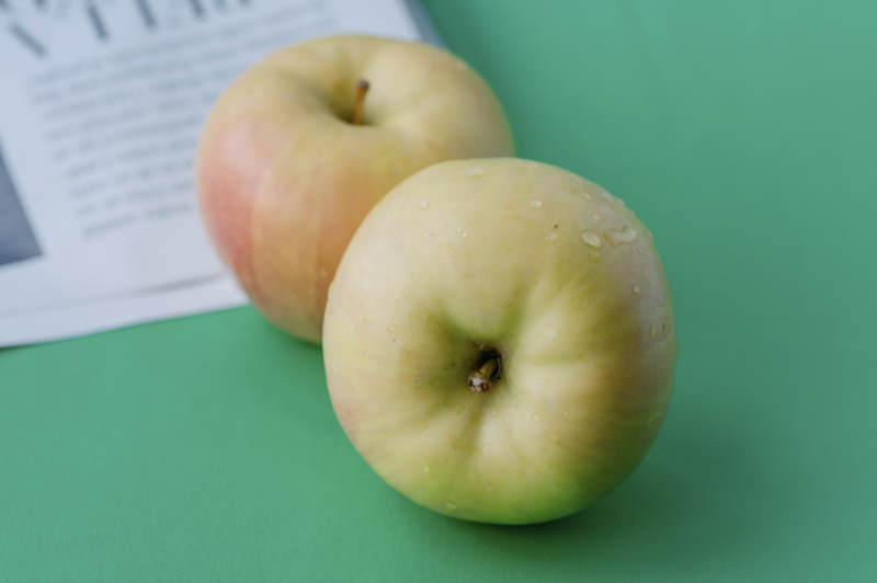 两颗青苹果静置于绿桌图片