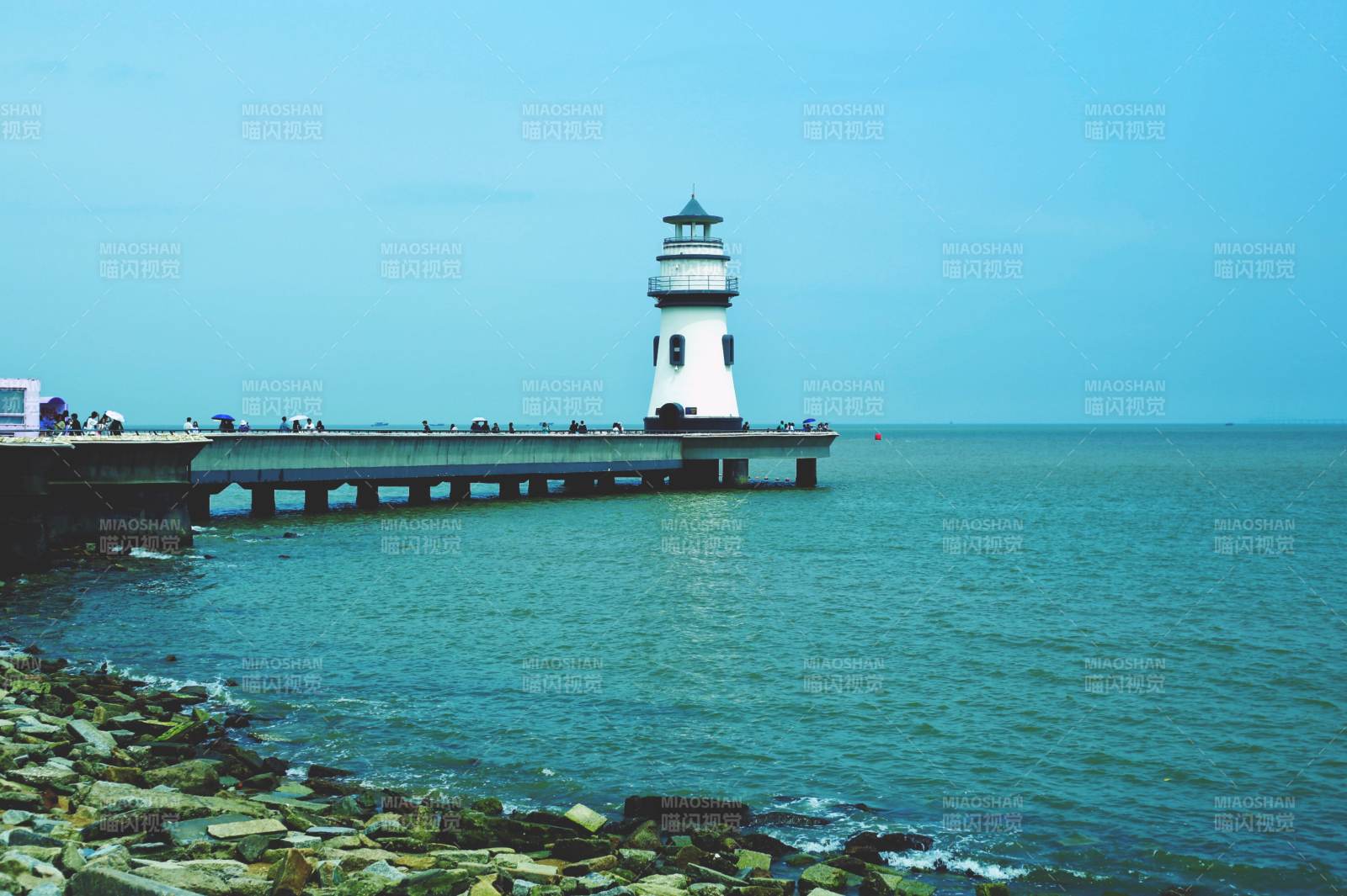 海边灯塔与石堤风景图片