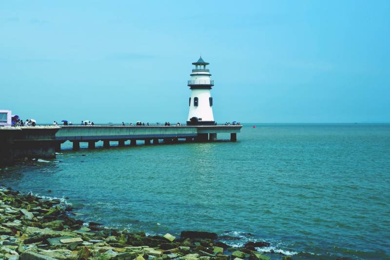 海边灯塔与石堤风景图片