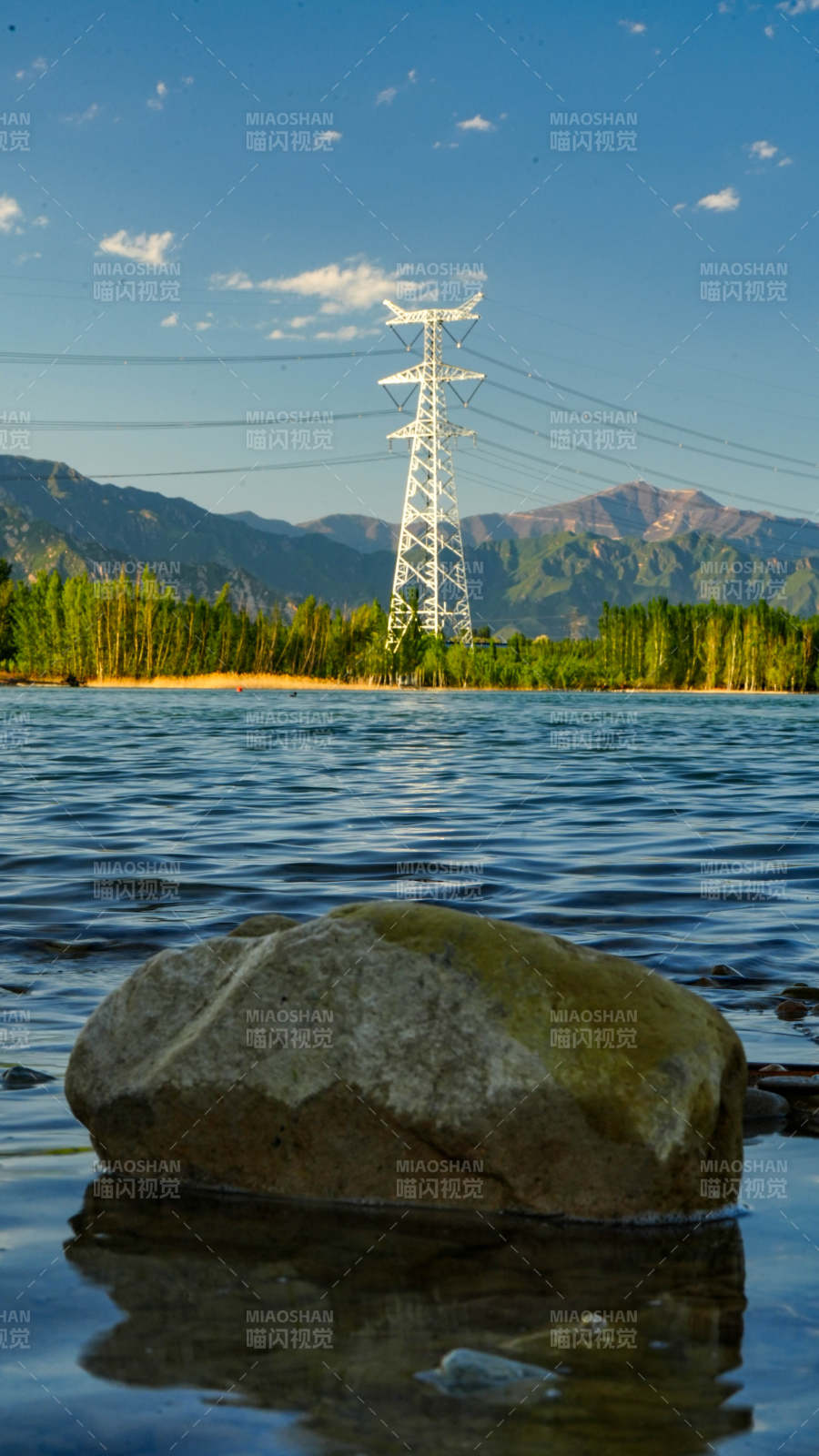 湖畔巨石与远山输电塔图片