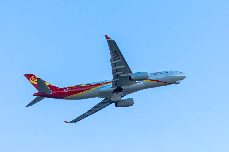 红色涂装的飞机在蓝天中飞行图片