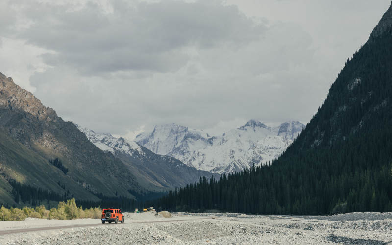 伊犁雪山峡谷中的橙色越野车图片