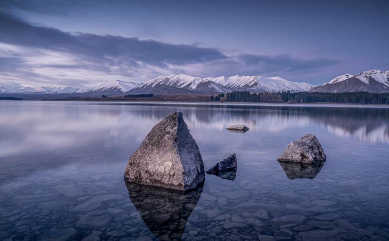 湖畔巨石映雪山图片