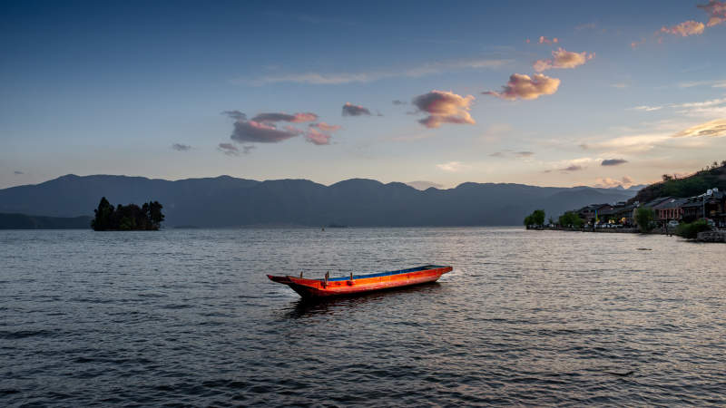 泸沽湖畔日落中的小舟图片