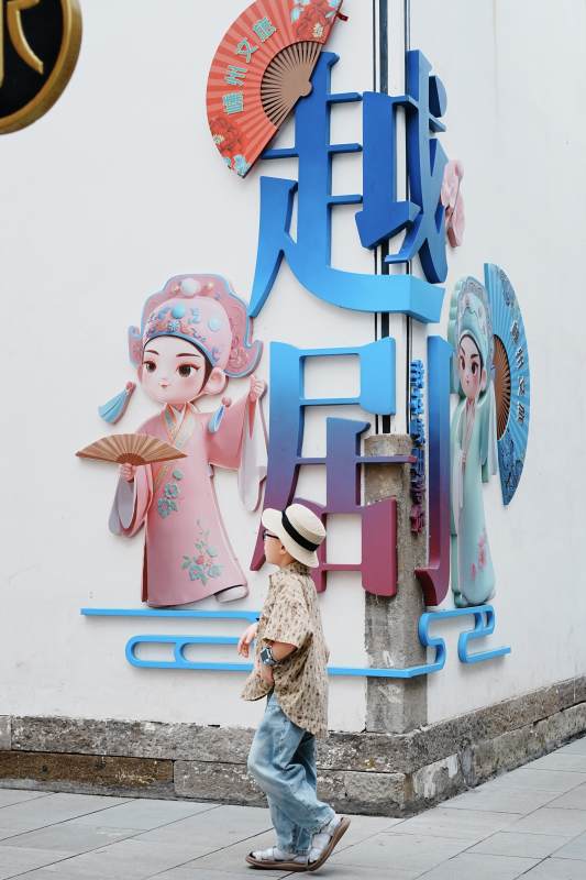 越剧文化墙前行人走过图片