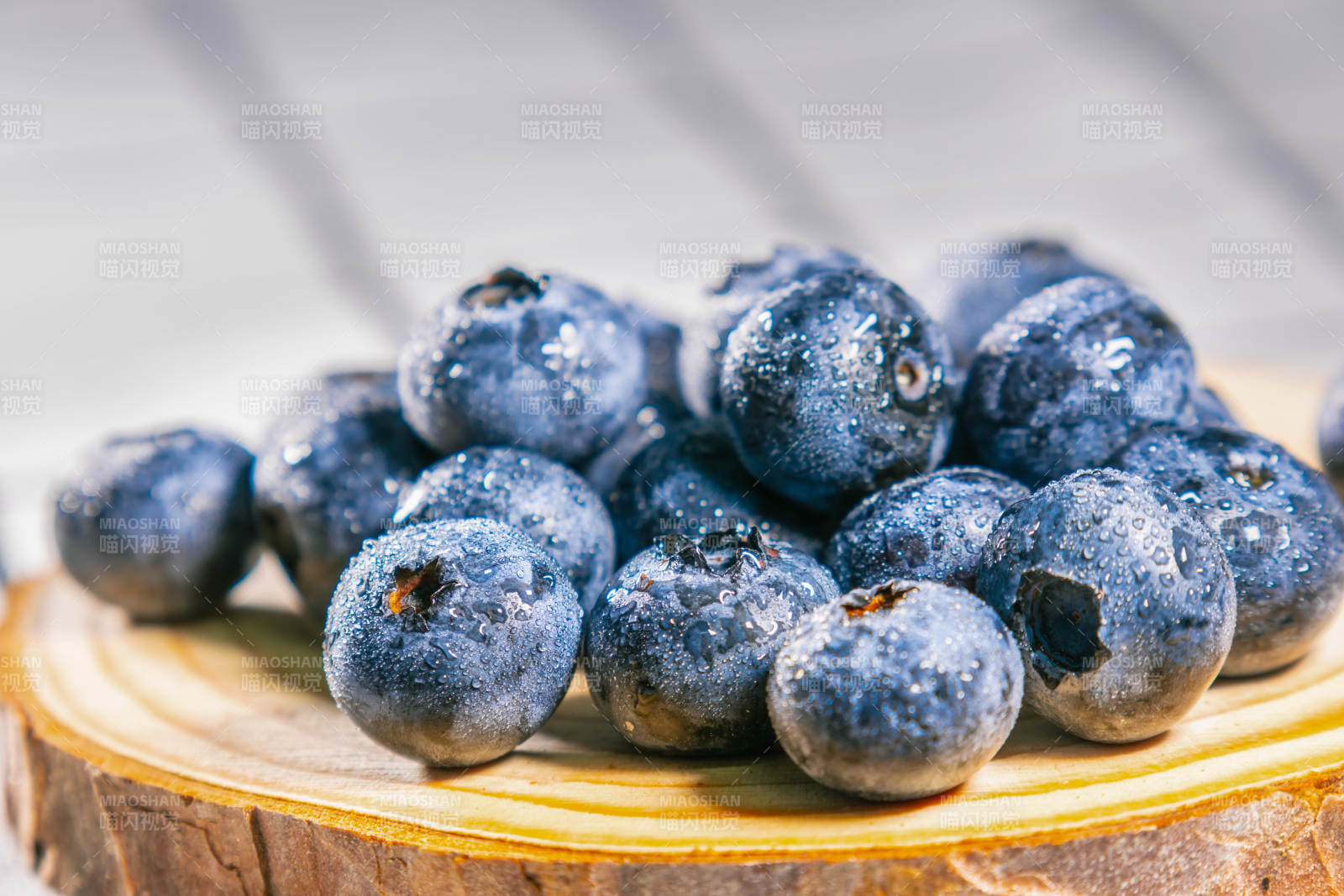 新鲜蓝莓堆叠在木盘上图片