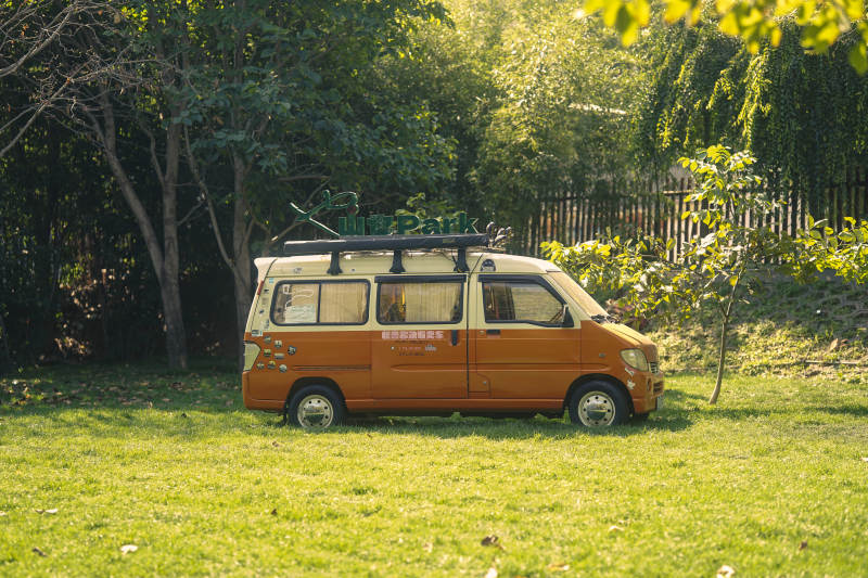 橙色面包车停绿草地图片