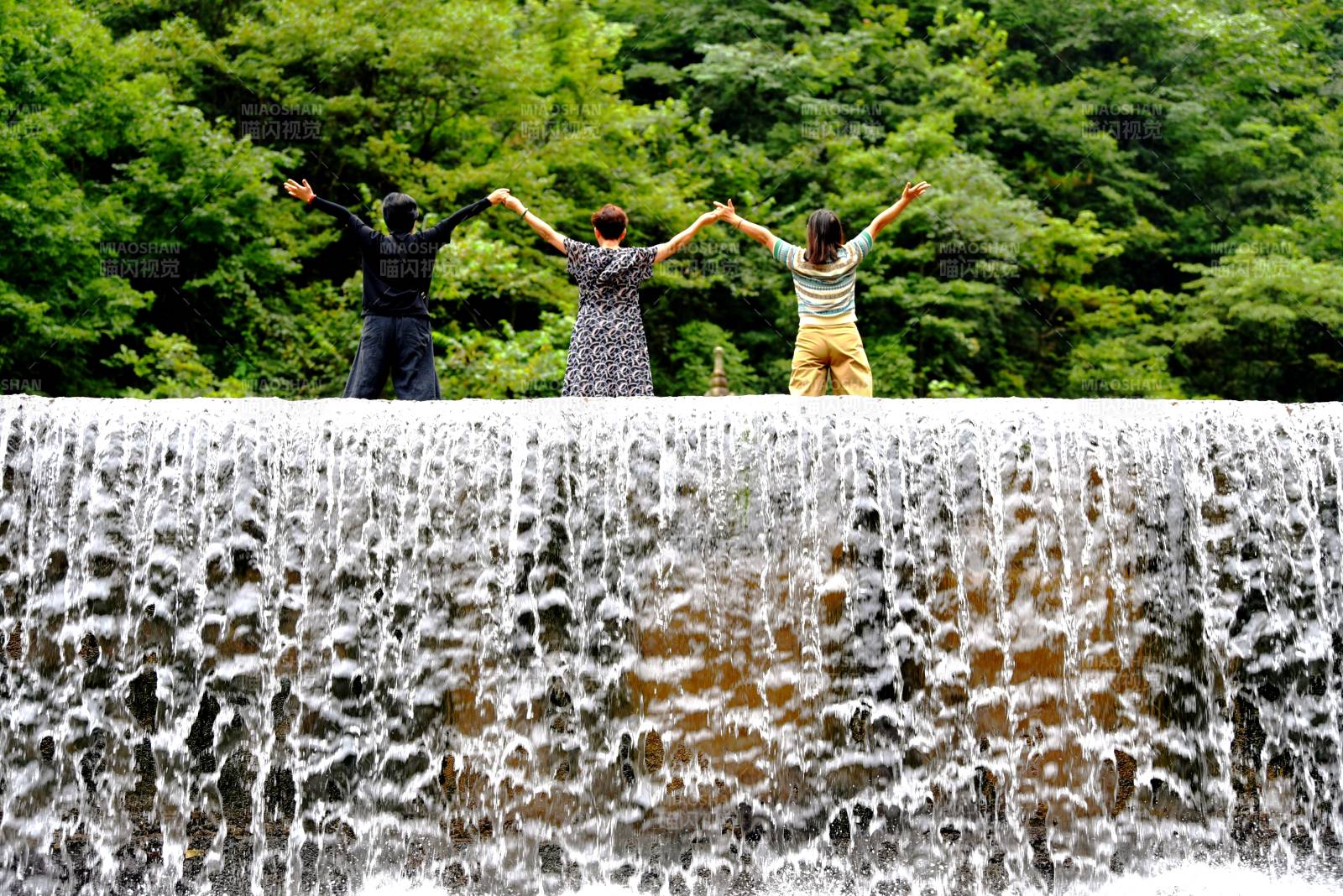 三人共赏瀑布美景图片