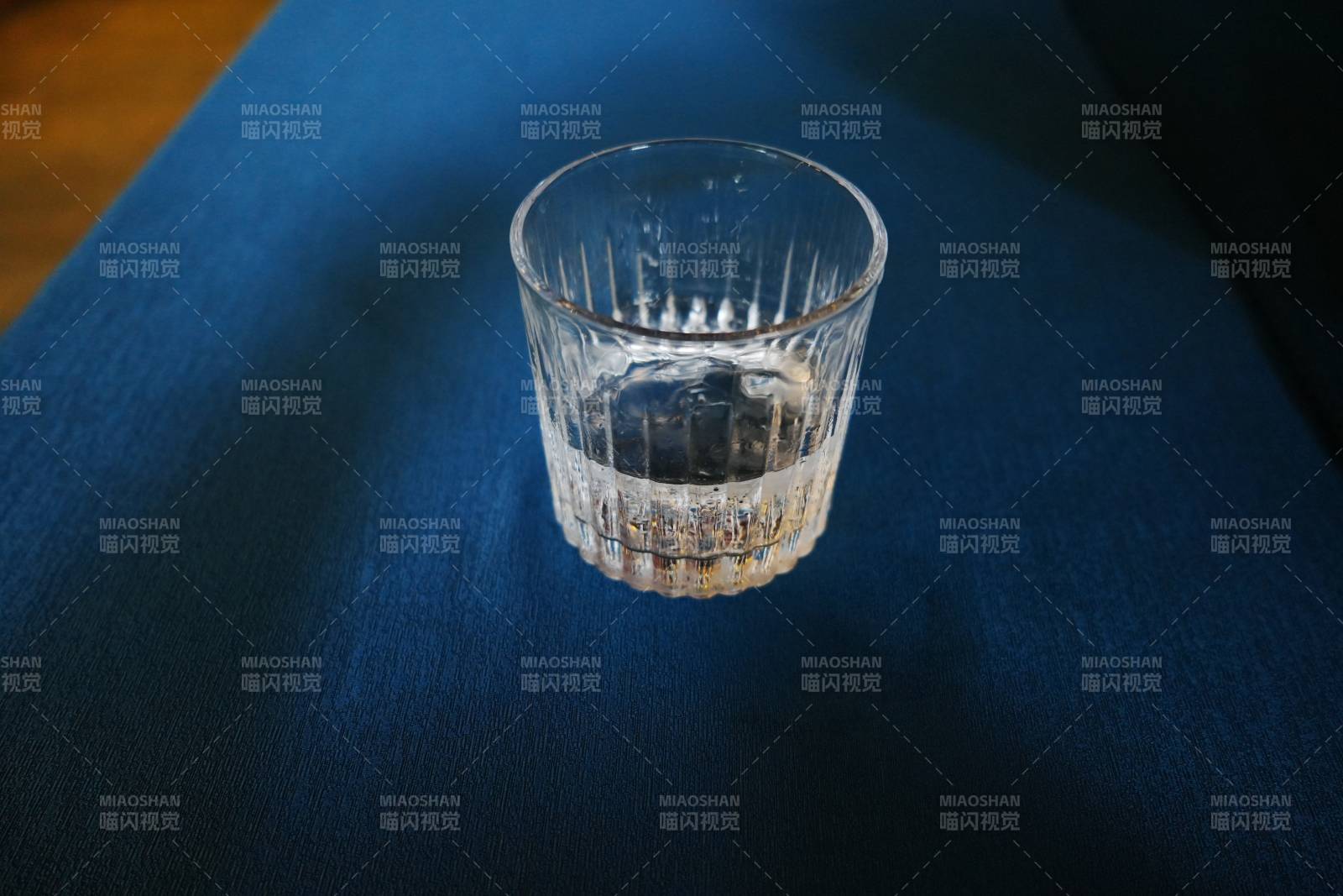 透明玻璃杯静置深蓝布上图片