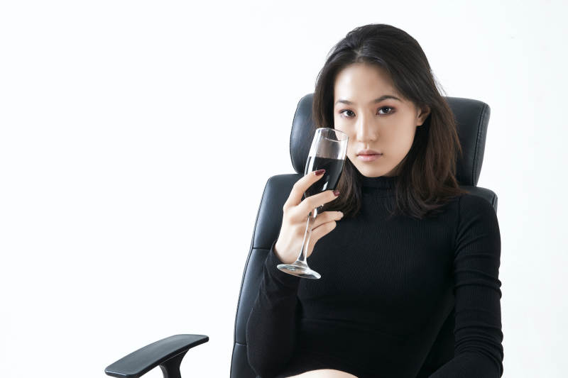 坐在椅子上独自品尝红酒的亚洲女性图片