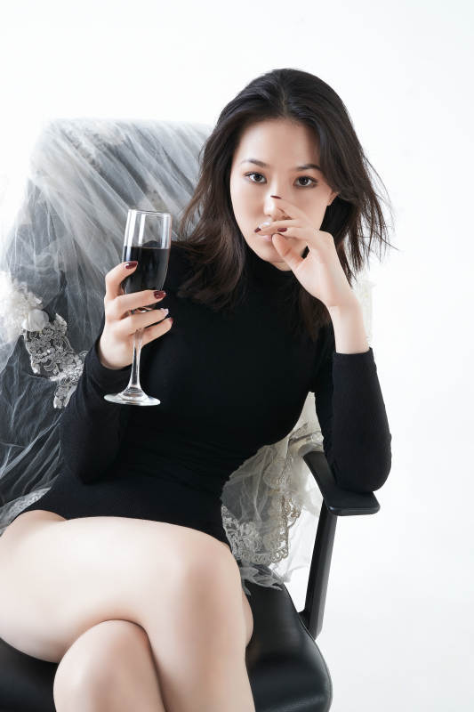 坐在椅子上独自品尝红酒的亚洲女性图片
