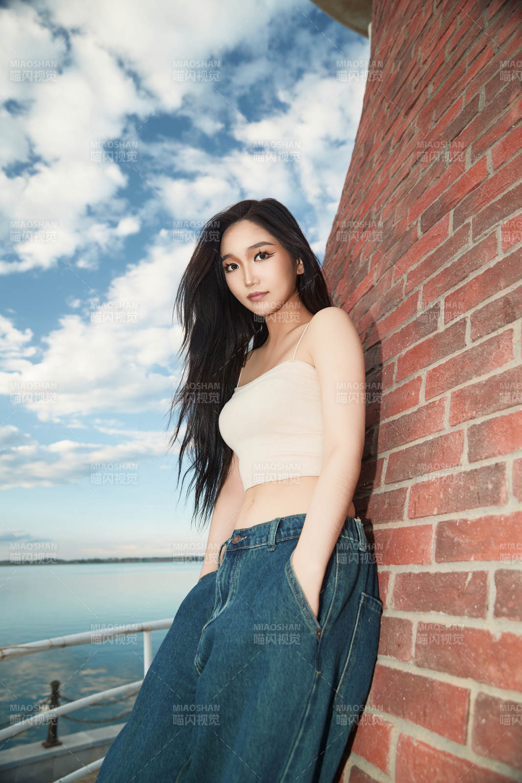 盛夏在景区湖边灯塔上拍照游玩的美女图片