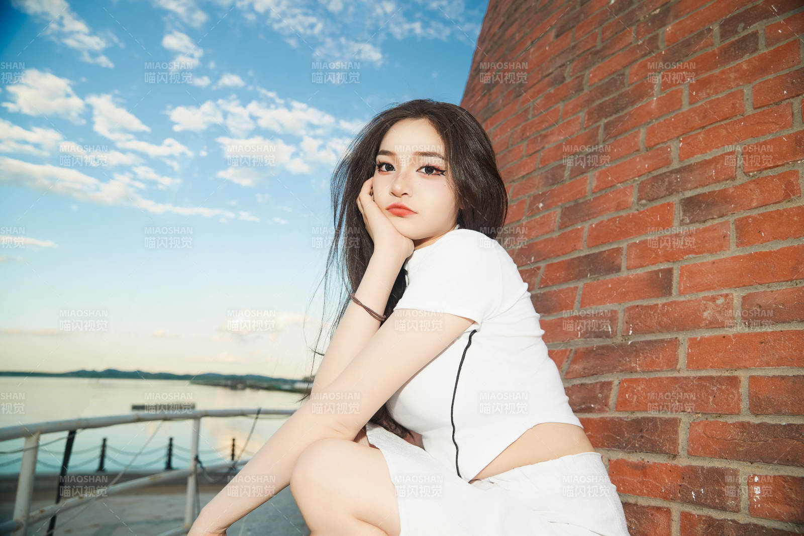 盛夏在景区湖边灯塔上拍照游玩的美女图片