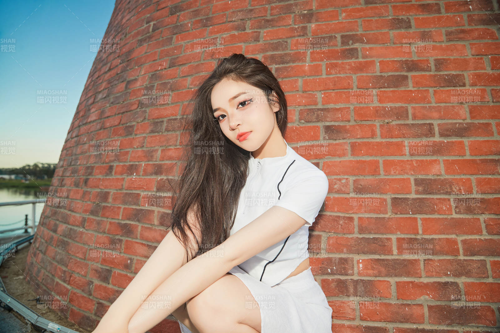 盛夏在景区湖边灯塔上拍照游玩的美女图片