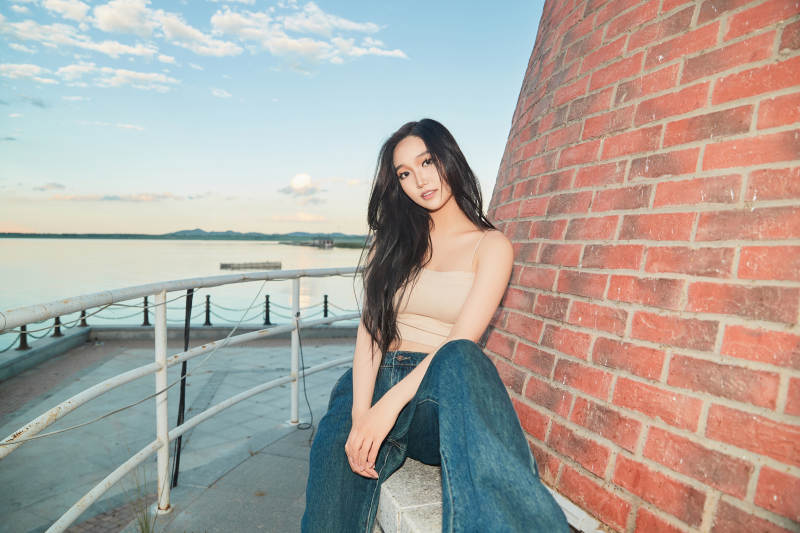 盛夏在景区湖边灯塔上拍照游玩的美女图片