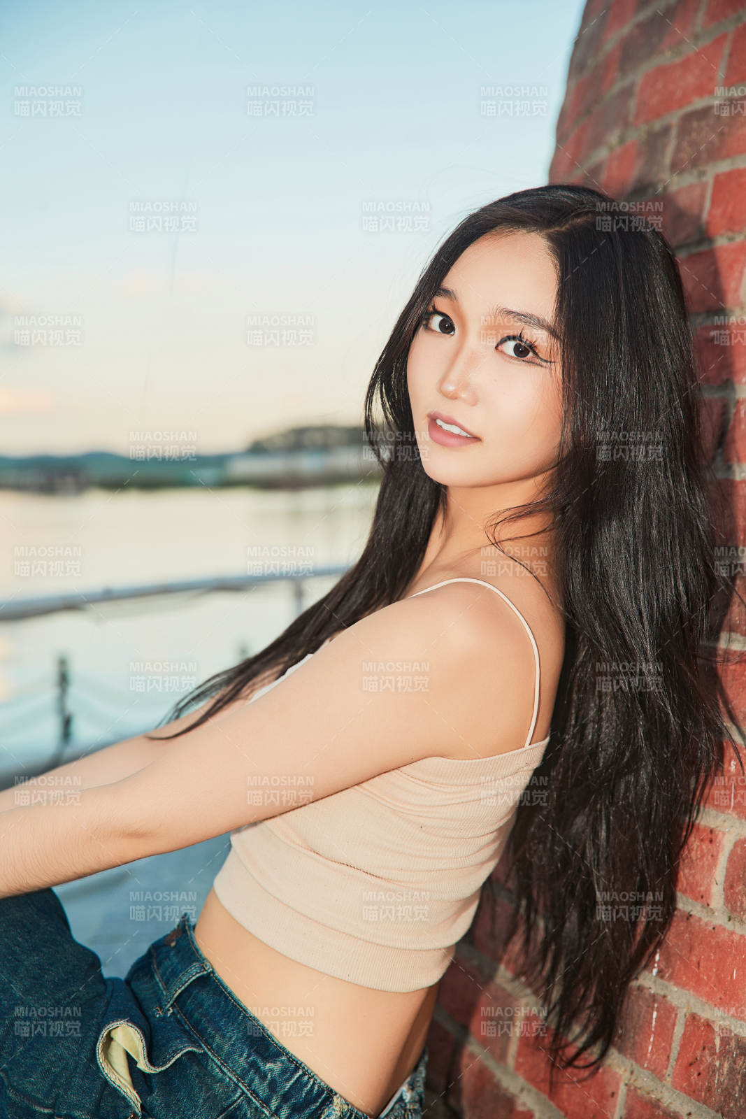 盛夏在景区湖边灯塔上拍照游玩的美女图片