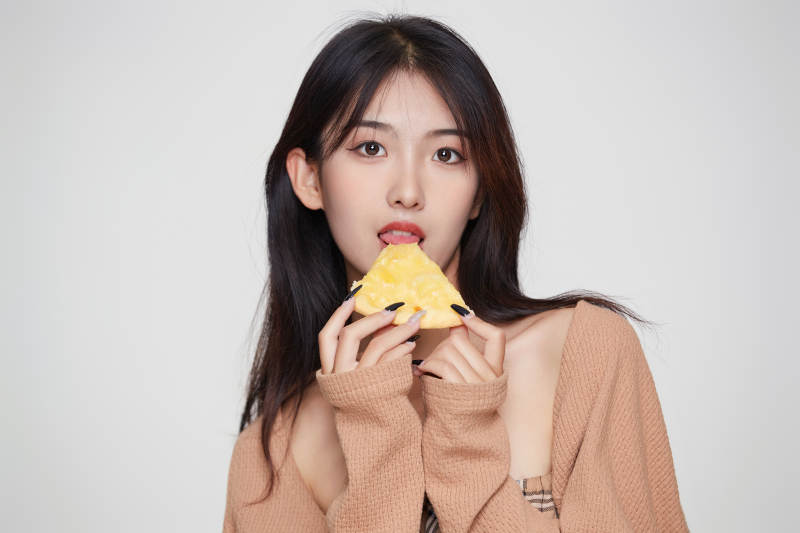 白色背景下吃着美味榴莲披萨的可爱少女图片