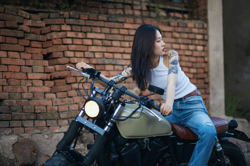 骑在复古摩托车上的时尚亚洲少女图片