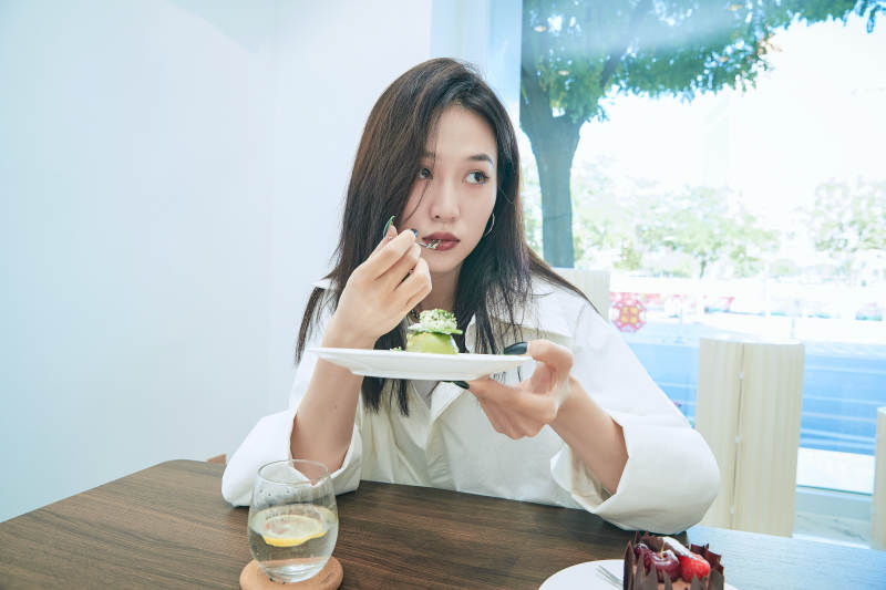 在烘焙店吃蛋糕喝饮料的可爱亚洲少女图片