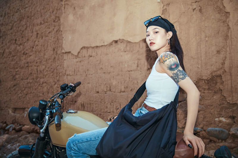 骑在复古摩托车上的时尚亚洲少女图片