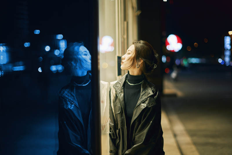 夜晚站立在橱窗外的亚洲少女图片