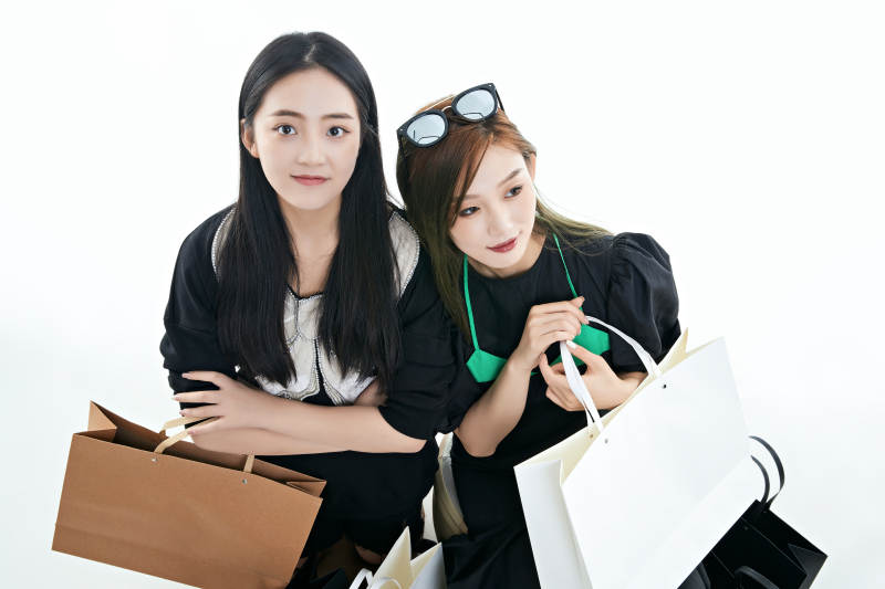 白色背景下手提购物袋时尚美丽的闺蜜图片