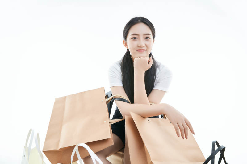 白色背景下手提购物袋时尚美丽的亚洲少女图片