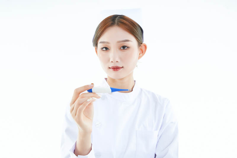 手持温度计的白衣女性医护人员图片
