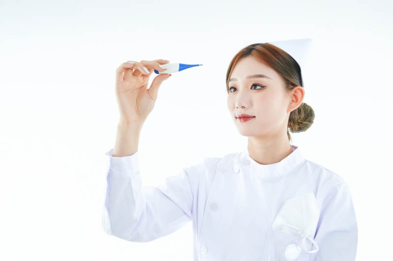 手持温度计的白衣女性医护人员图片