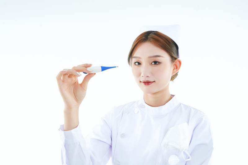 手持温度计的白衣女性医护人员图片
