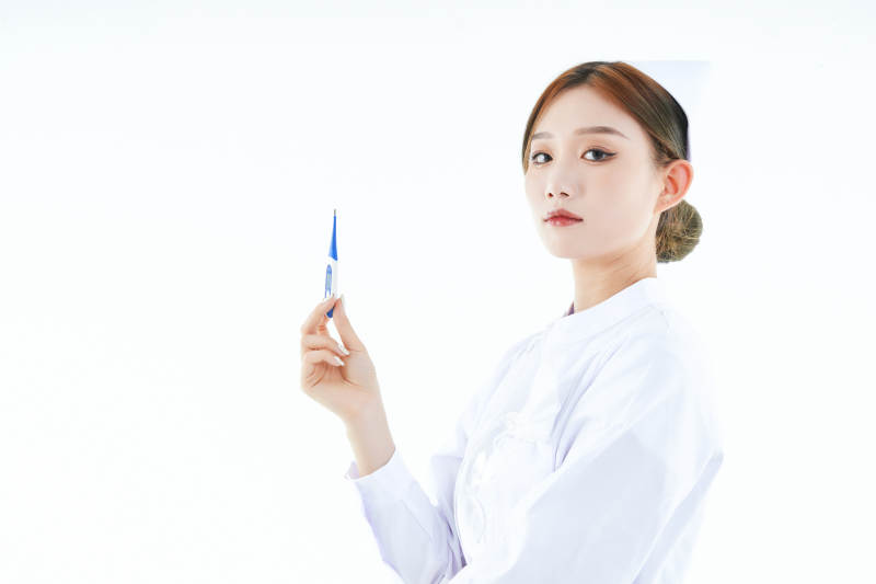 手持温度计的白衣女性医护人员图片