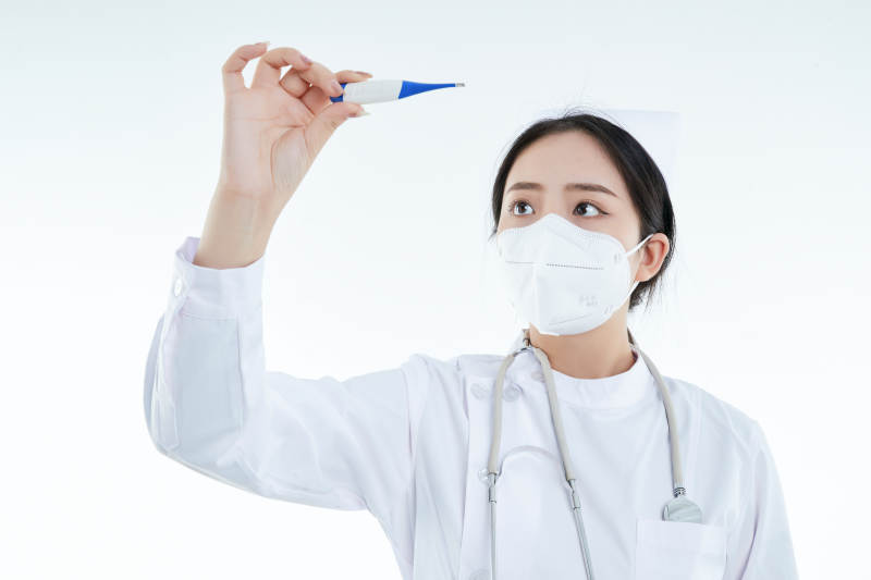 手持温度计的白衣女性医护人员图片