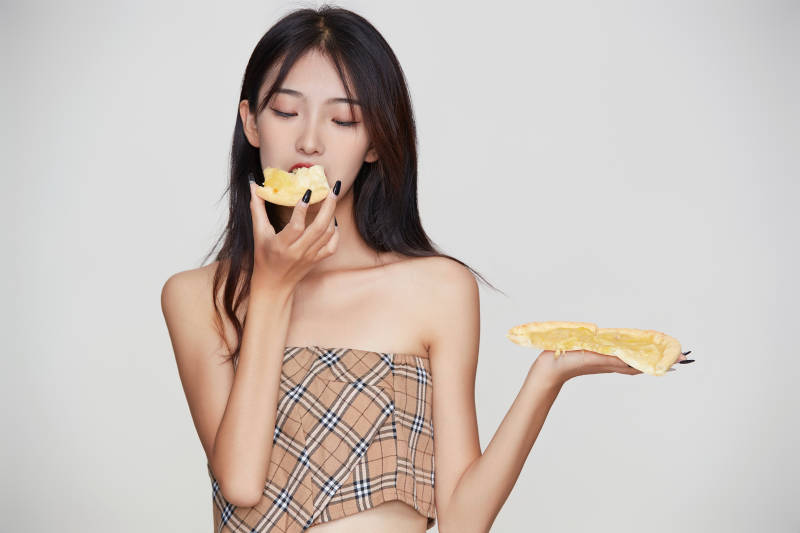 白色背景下吃着美味榴莲披萨的可爱少女图片