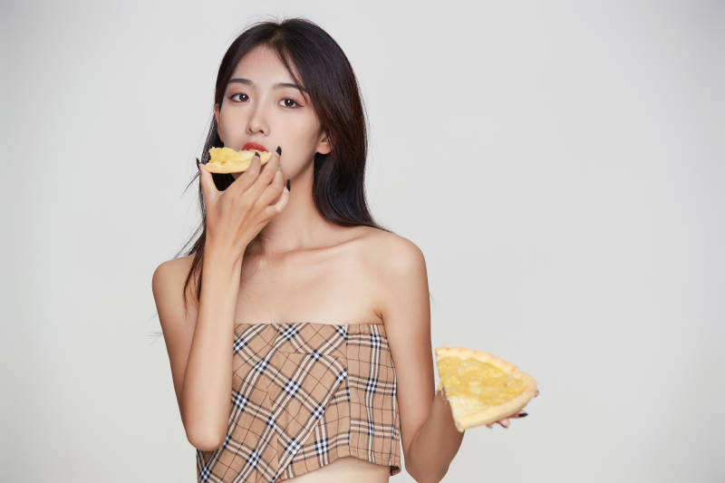 白色背景下吃着美味榴莲披萨的可爱少女图片