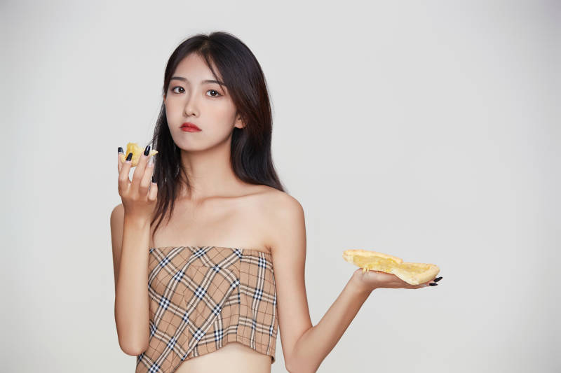 白色背景下吃着美味榴莲披萨的可爱少女图片