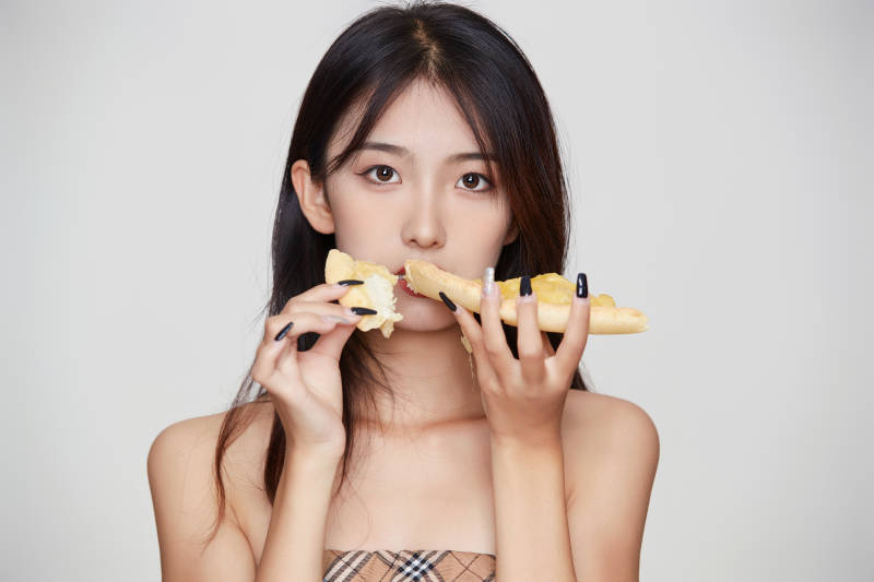 白色背景下吃着美味榴莲披萨的可爱少女图片