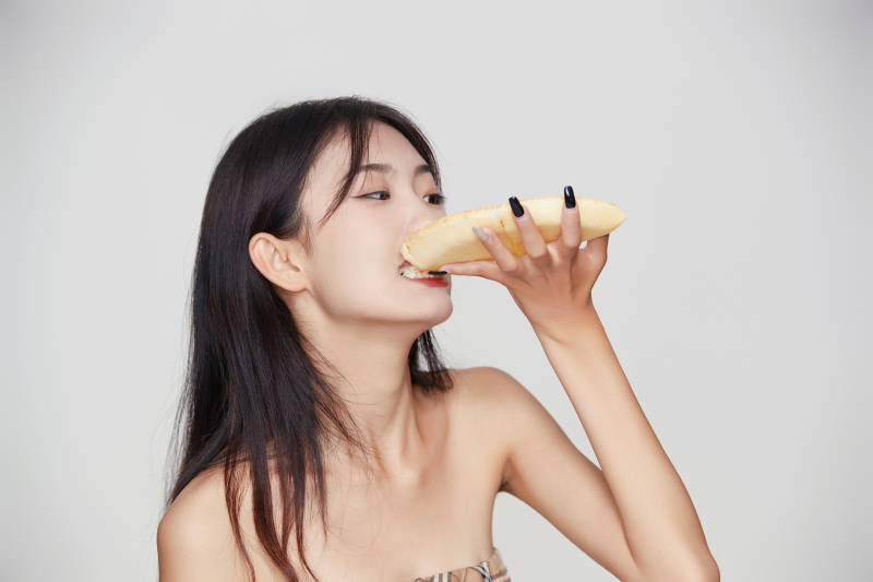 白色背景下吃着美味榴莲披萨的可爱少女图片