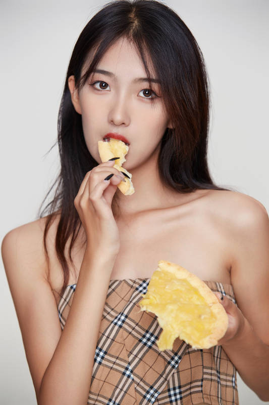 白色背景下吃着美味榴莲披萨的可爱少女图片