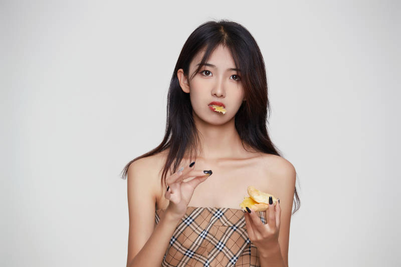 白色背景下吃着美味榴莲披萨的可爱少女图片