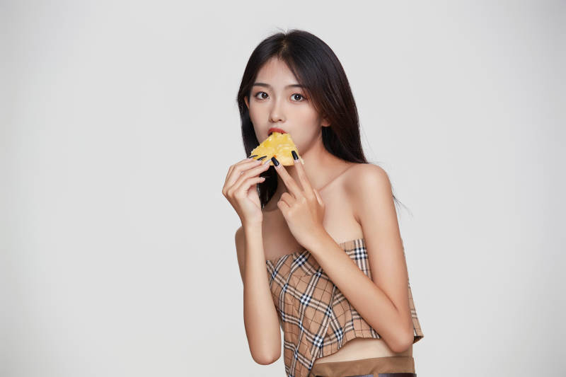 白色背景下吃着美味榴莲披萨的可爱少女图片