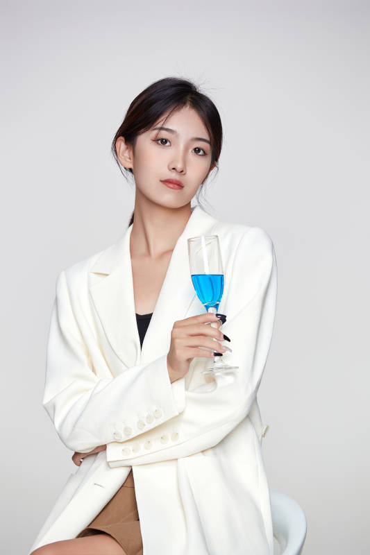 坐在椅子上手端酒杯的亚洲商务女性图片