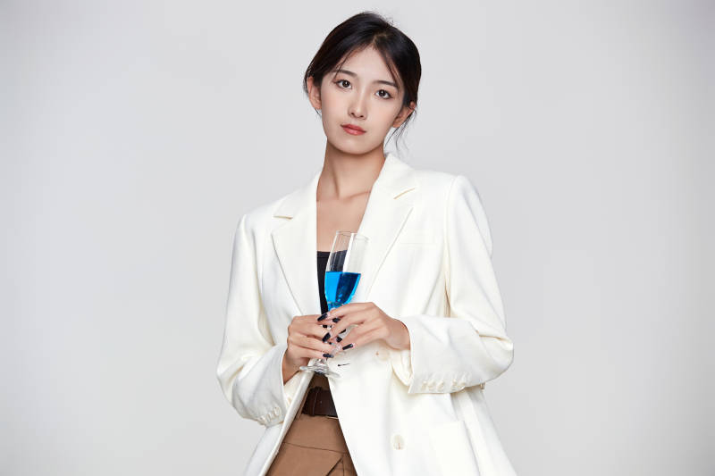 坐在椅子上手端酒杯的亚洲商务女性图片