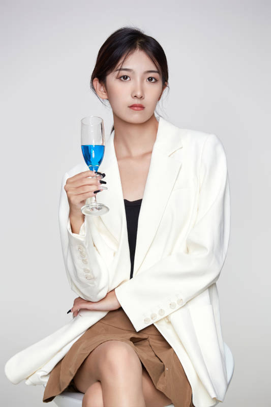 坐在椅子上手端酒杯的亚洲商务女性图片