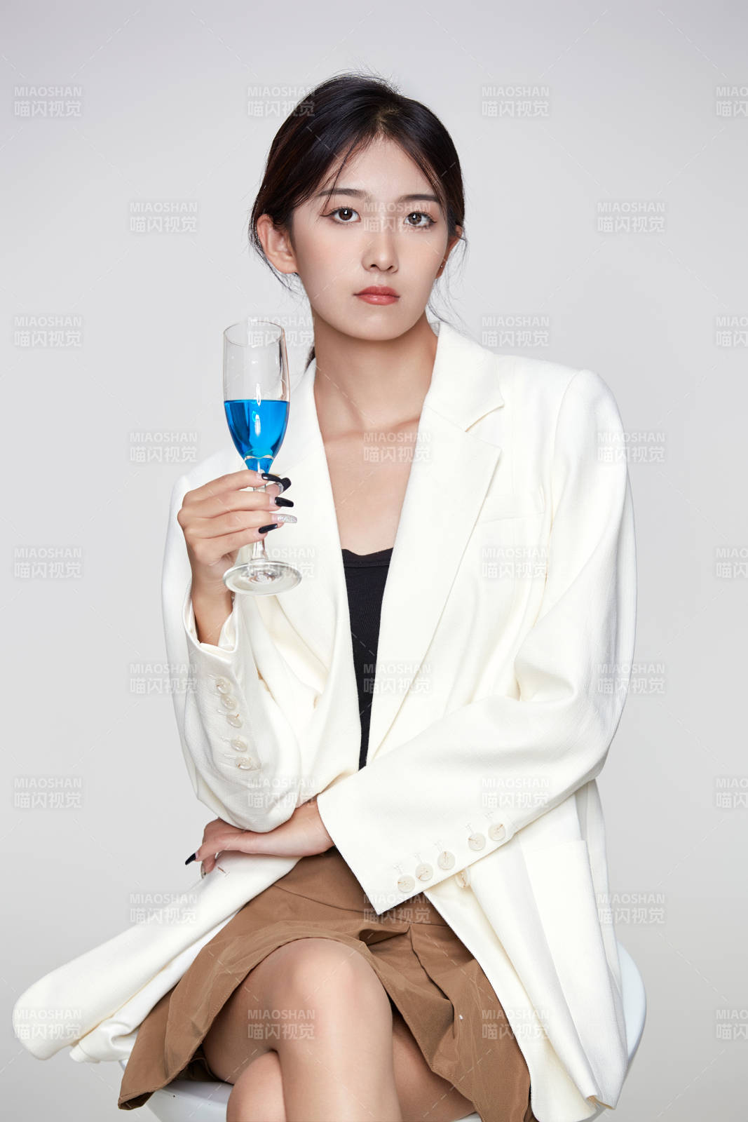 坐在椅子上手端酒杯的亚洲商务女性图片