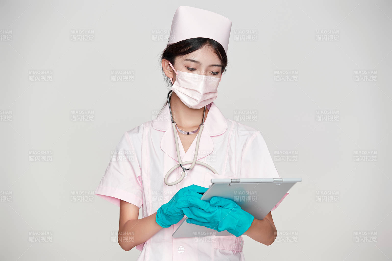 身穿粉色护士服佩戴听诊器的女性医护人员图片