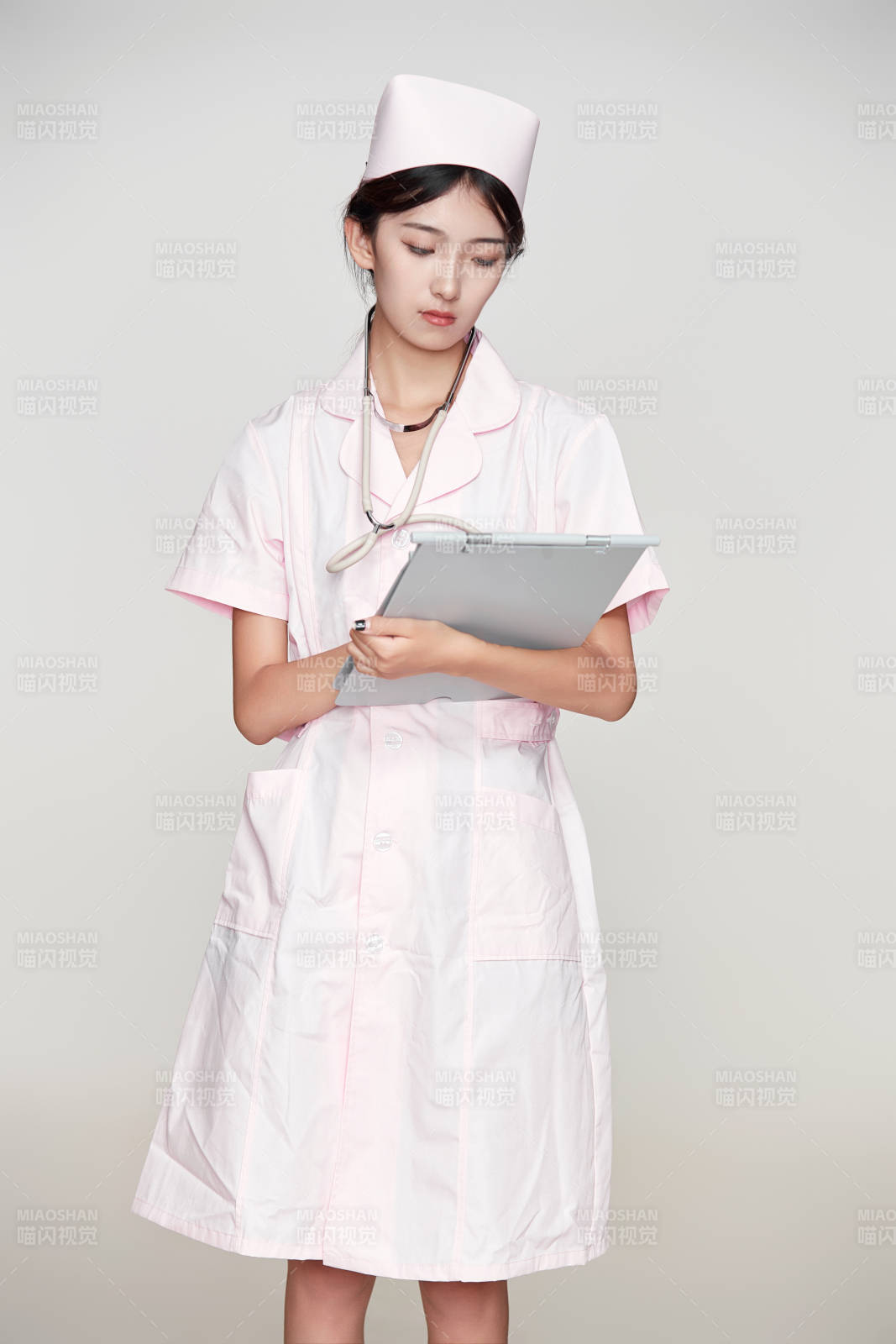身穿粉色护士服佩戴听诊器的女性医护人员图片
