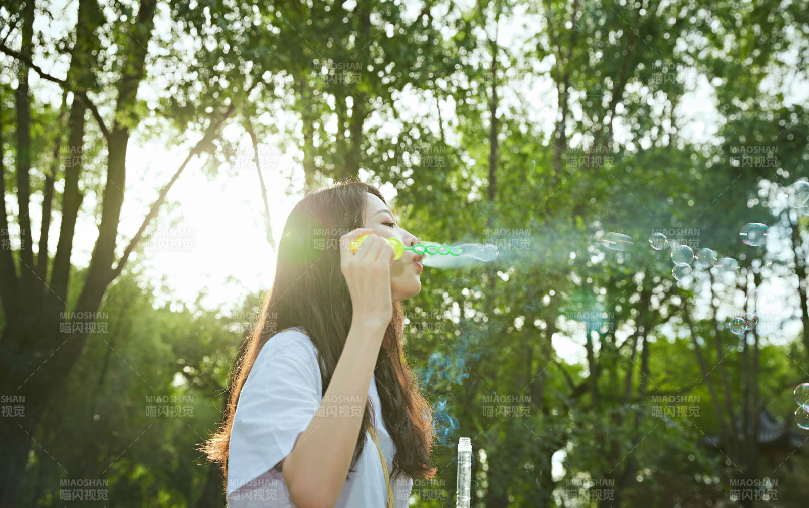 户外公园里玩吹泡泡的可爱亚洲少女图片