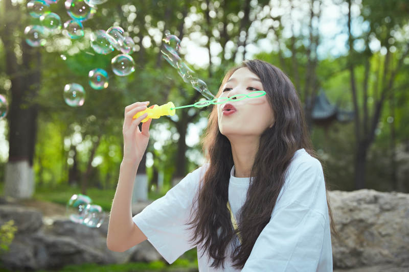 户外公园里玩吹泡泡的可爱亚洲少女图片